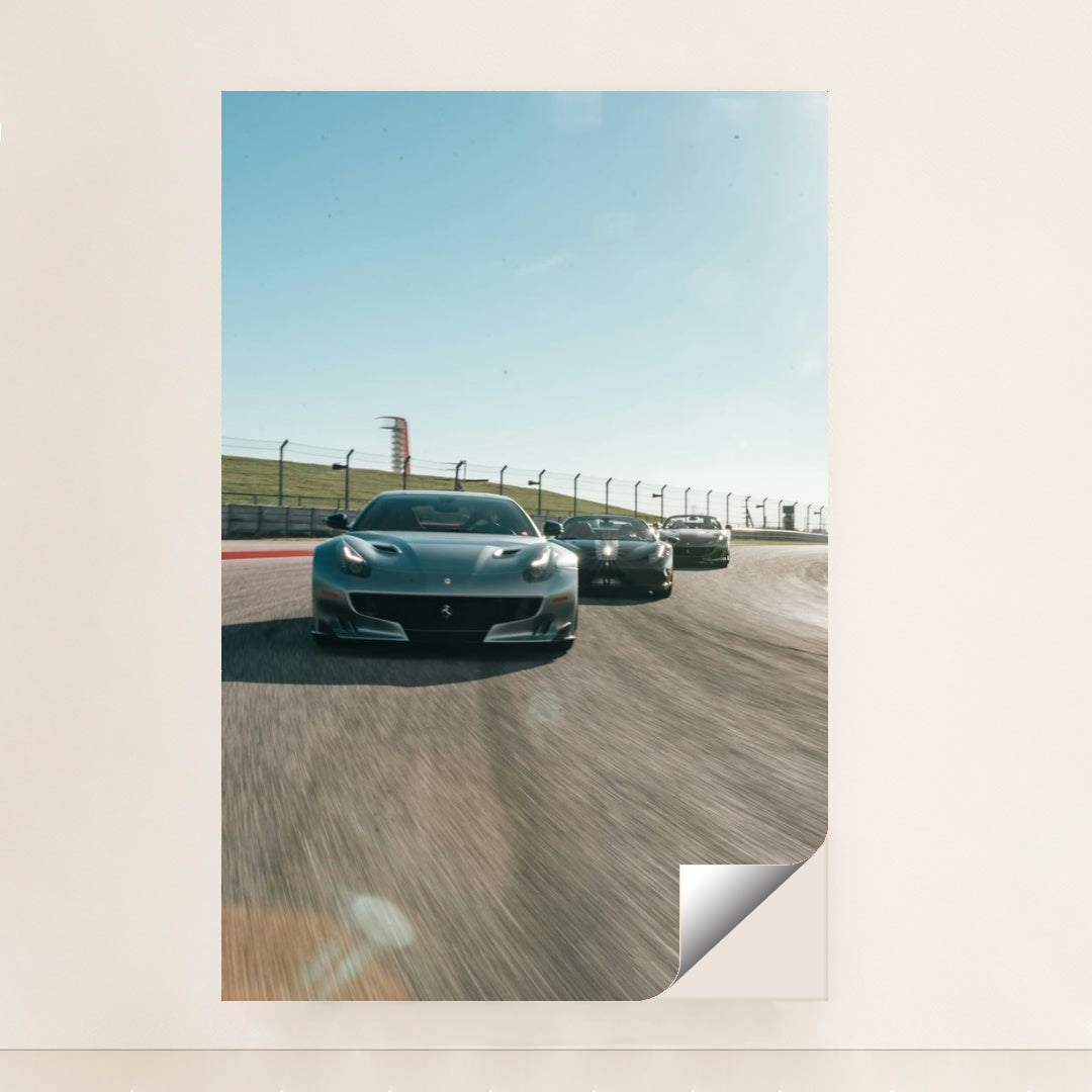 This photo shows three grey Ferrari sports cars racing side by side on a sunny racetrack, minimalist unframed style.