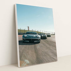 This photo shows three grey Ferrari sports cars racing side by side on a sunny racetrack, in a white frame.