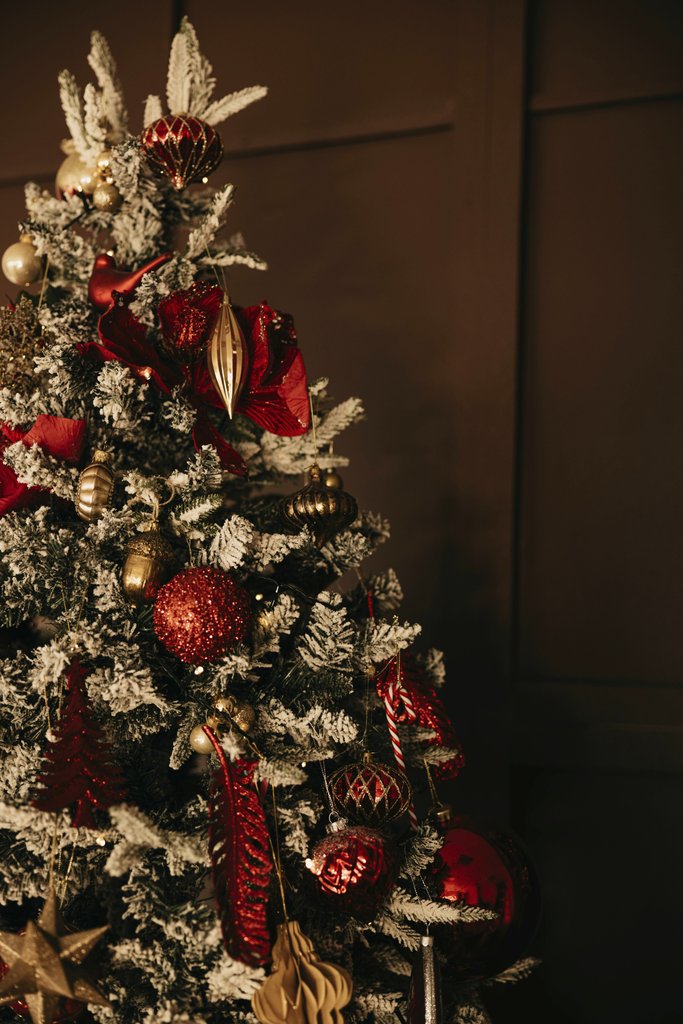 Lisett Kruusim - Beautifully decorated Christmas tree with red and gold ornaments in a cozy indoor setting.