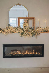 Valeria Boltneva - A beautifully decorated fireplace for Christmas with candles, greenery, and a festive reflection in mirrors.