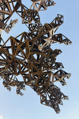 Mohamed Sameer - Intricate metal sculpture with geometric design set against a clear blue sky.
