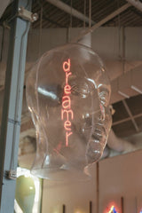 Raphael Loquellano - Close-up of a transparent head sculpture with a neon 'dreamer' sign inside, creating an artistic effect.