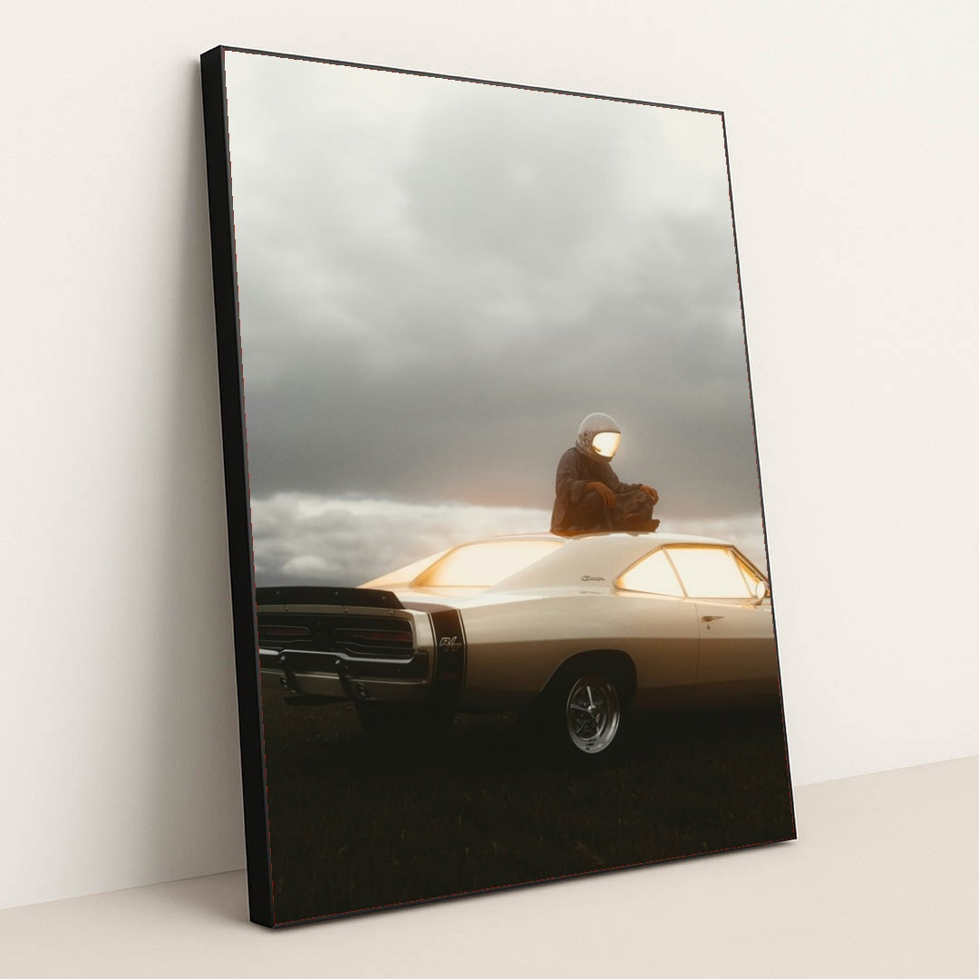 This photo shows a person in an astronaut suit sitting on the roof of a classic Dodge Charger at dusk, in a black frame.