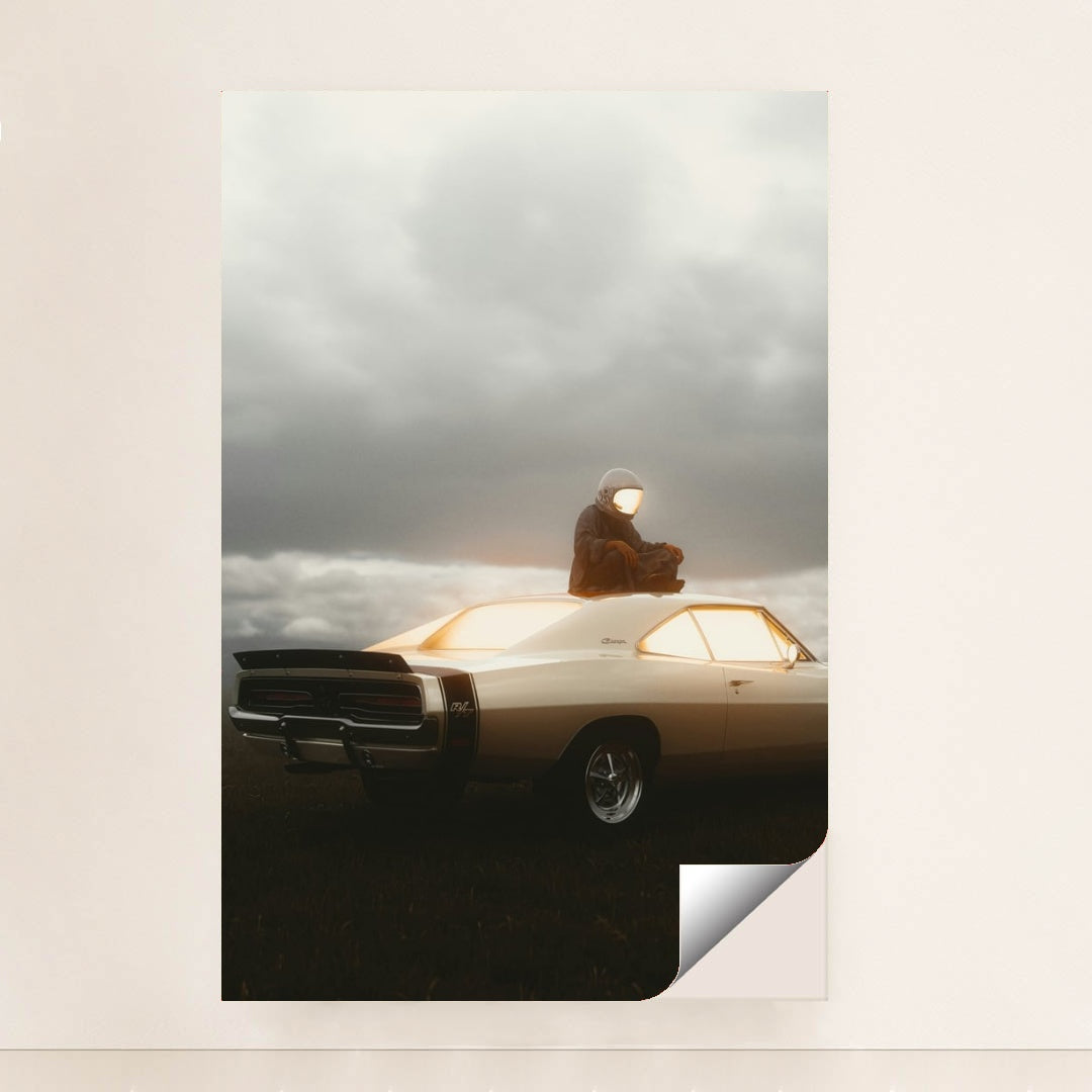 This photo shows a person in an astronaut suit sitting on the roof of a classic Dodge Charger at dusk, unframed.