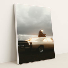 This photo shows a person in an astronaut suit sitting on the roof of a classic Dodge Charger at dusk, in a white frame.