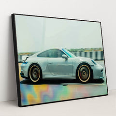 This photo shows a silver Porsche sports car in motion on a highway with colorful reflections on the road, in a black frame.