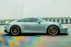 Silver Porsche 911 in Motion, sleek car wall art featuring gold wheels and red brake calipers on a blurred road.