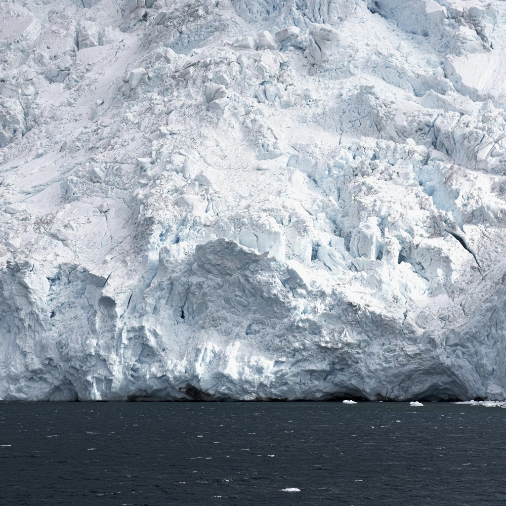 Hugo Sykes - A stunning view of a frosty iceberg towering over a cold, dark ocean under a polar climate.