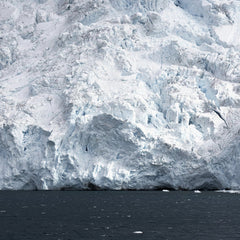 Hugo Sykes - A stunning view of a frosty iceberg towering over a cold, dark ocean under a polar climate.