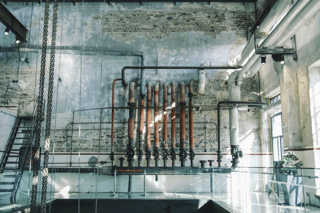 Sami TÜRK - Rustic industrial scene featuring vintage pipes and brick walls in an old warehouse setting.