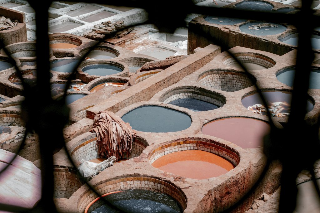 Taken by Great - Aerial view of colorful dyeing vats in a traditional Moroccan leather tannery, vibrant textile scene.