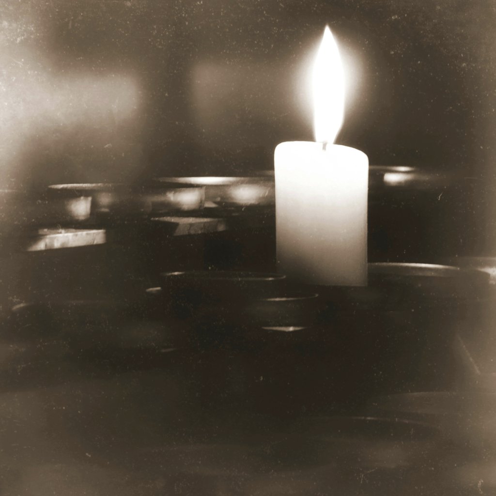 Suzy Hazelwood - A single candle burning brightly, casting a warm glow in sepia-toned ambiance.