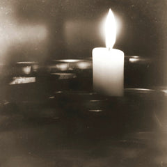 Suzy Hazelwood - A single candle burning brightly, casting a warm glow in sepia-toned ambiance.