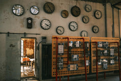 Sami TÜRK - An array of vintage wall clocks in a dimly lit industrial setting, highlighting time and nostalgia.