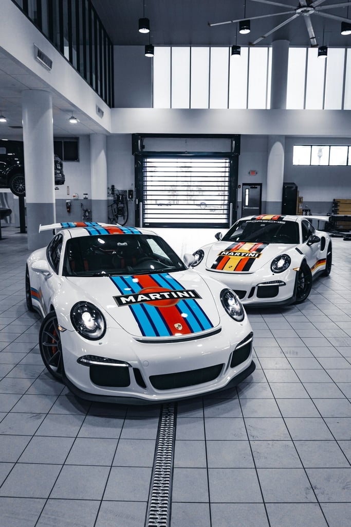 Duo Porsche 911 GT3 Icons in Martini Livery showcased in a modern workshop, highlighting car wall art.