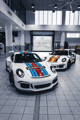 Duo Porsche 911 GT3 Icons in Martini Livery showcased in a modern workshop, highlighting car wall art.