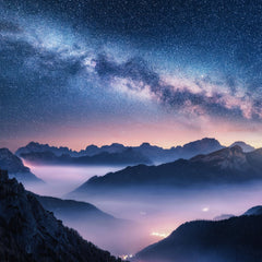 Stock Photos - Milky Way over mountains in fog at night in summer. Landscape with foggy alpine mountain valley, purple low clouds, colorful starry sky with milky way, city illumination. Dolomites, Italy. Space