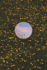 NIKOLAOS CHALKIDIS - A round mirror reflects the colorful sunset amidst a meadow of blooming wildflowers in Athens.