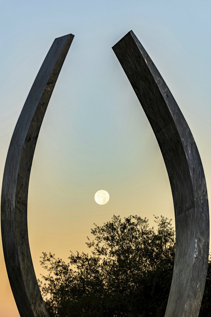 Siva Seshappan - Capture of the moon at sunset, framed by metal arches in Merced, CA.