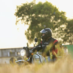 Nishant Aneja - A biker riding a Royal Enfield through a sunny field under a clear sky.