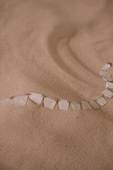 cottonbro studio - A delicate necklace displayed on smooth sand, highlighting texture and elegance.