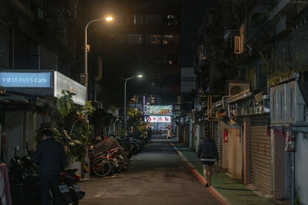 Jimmy Liao - A quiet urban alley at night with streetlights, shop signs, and parked motorcycles creating a serene atmosphere.