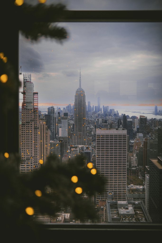 Steve Cancel - View of New York City skyline with Empire State Building through holiday decor. Perfect for travel and winter imagery.