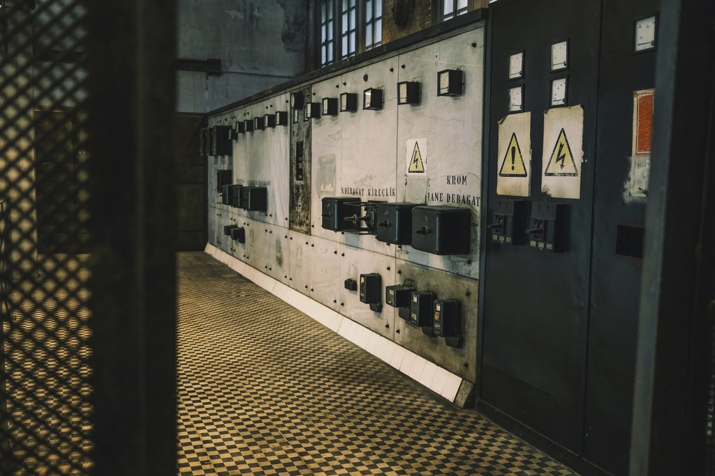 Sami TÜRK - Vintage industrial control panel with warning signs in a dimly lit room, creating a moody atmosphere.