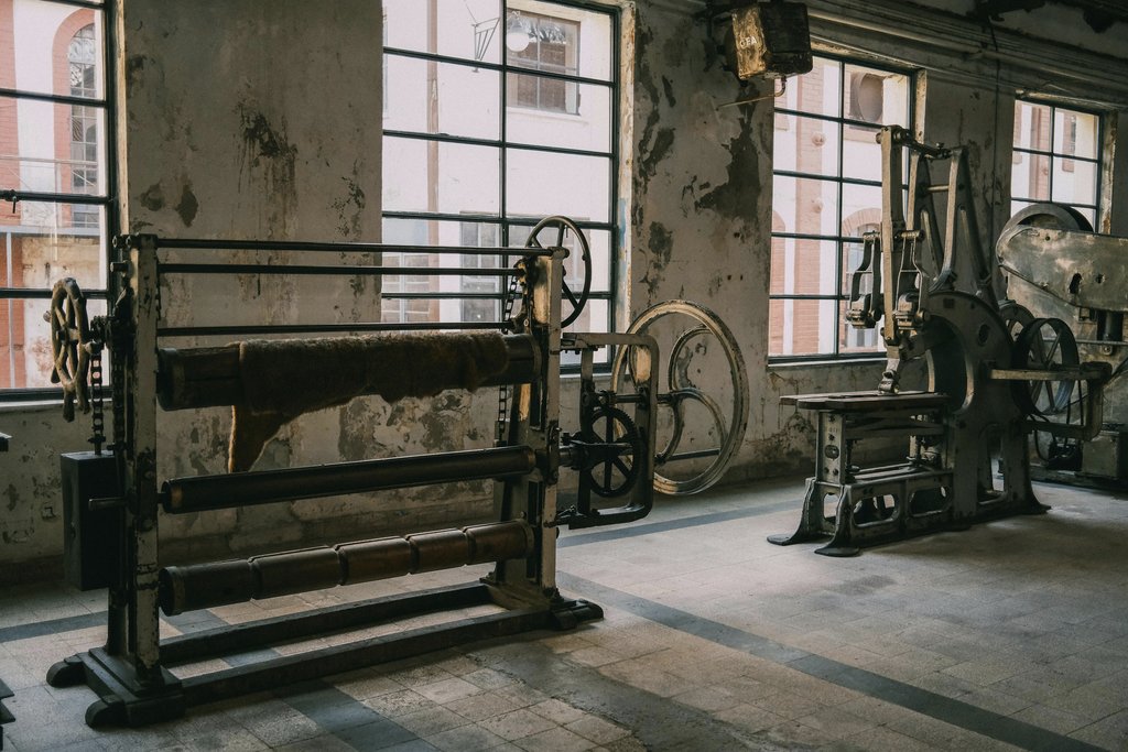 Sami TÜRK - Old industrial machines in a rustic, abandoned factory with textured walls.