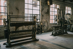 Sami TÜRK - Old industrial machines in a rustic, abandoned factory with textured walls.