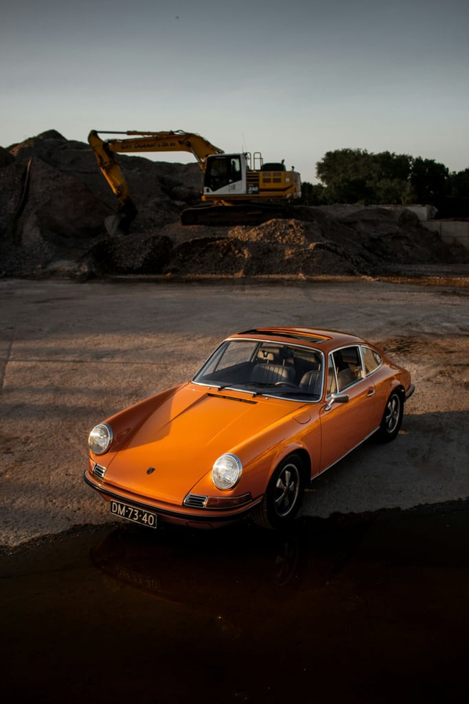 Black Porsche Coupe on Excavated Terrain with orange details against rugged construction backdrop.