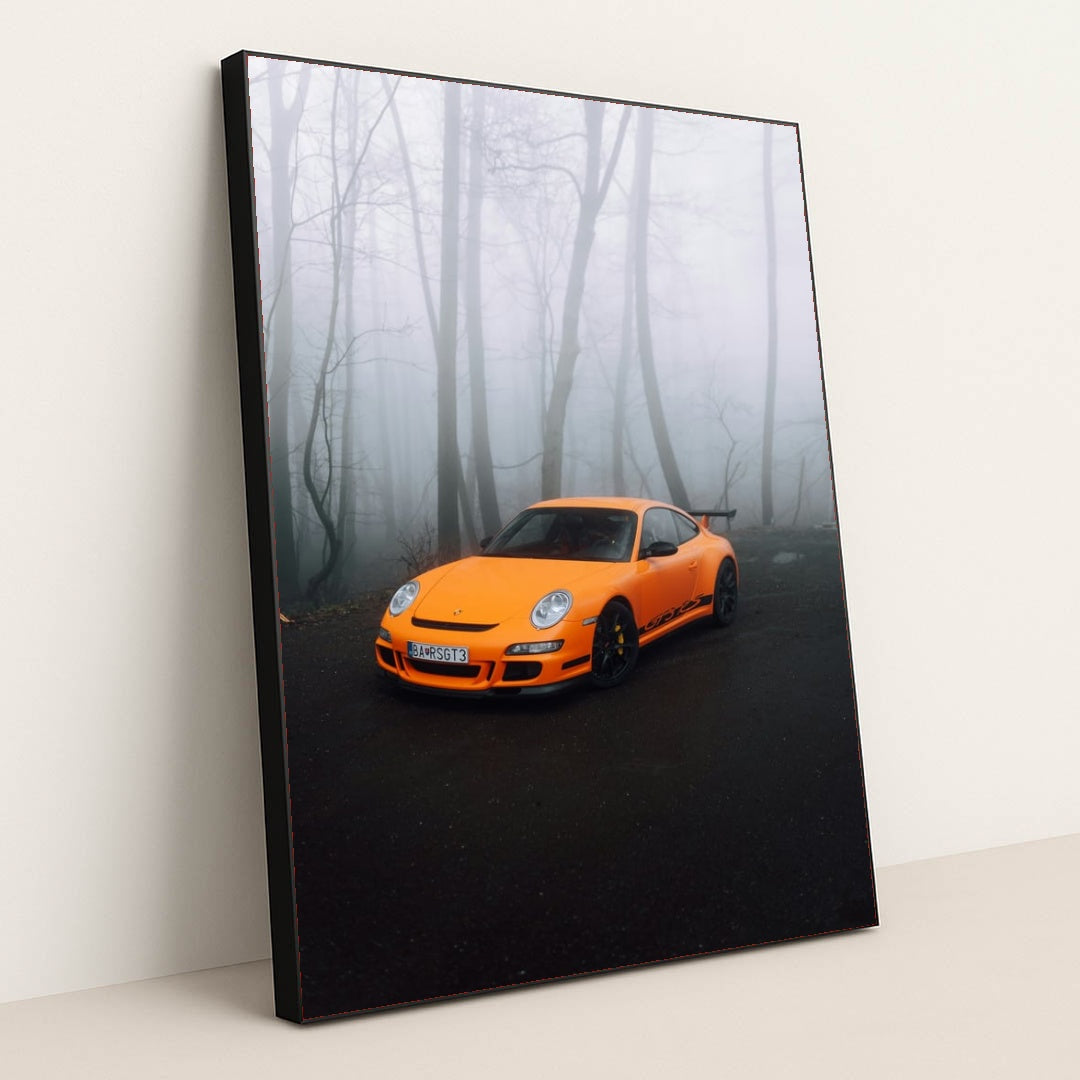 This photo shows an orange Porsche sports car parked on a misty forest road, in a black frame.