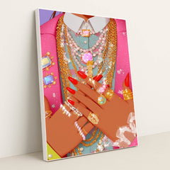 This artwork shows hands with red nails adorned with multiple sparkling gold and silver rings and necklaces over a pink jacket, in a white frame.