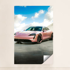 This photo shows a pink Porsche Taycan electric sports car parked outside under a blue sky with clouds, minimalist unframed style.