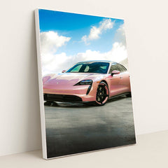 This photo shows a pink Porsche Taycan electric sports car parked outside under a blue sky with clouds, in a white frame.