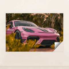 This photo shows a pink Porsche sports car with black stripes parked near tropical palm trees, unframed.