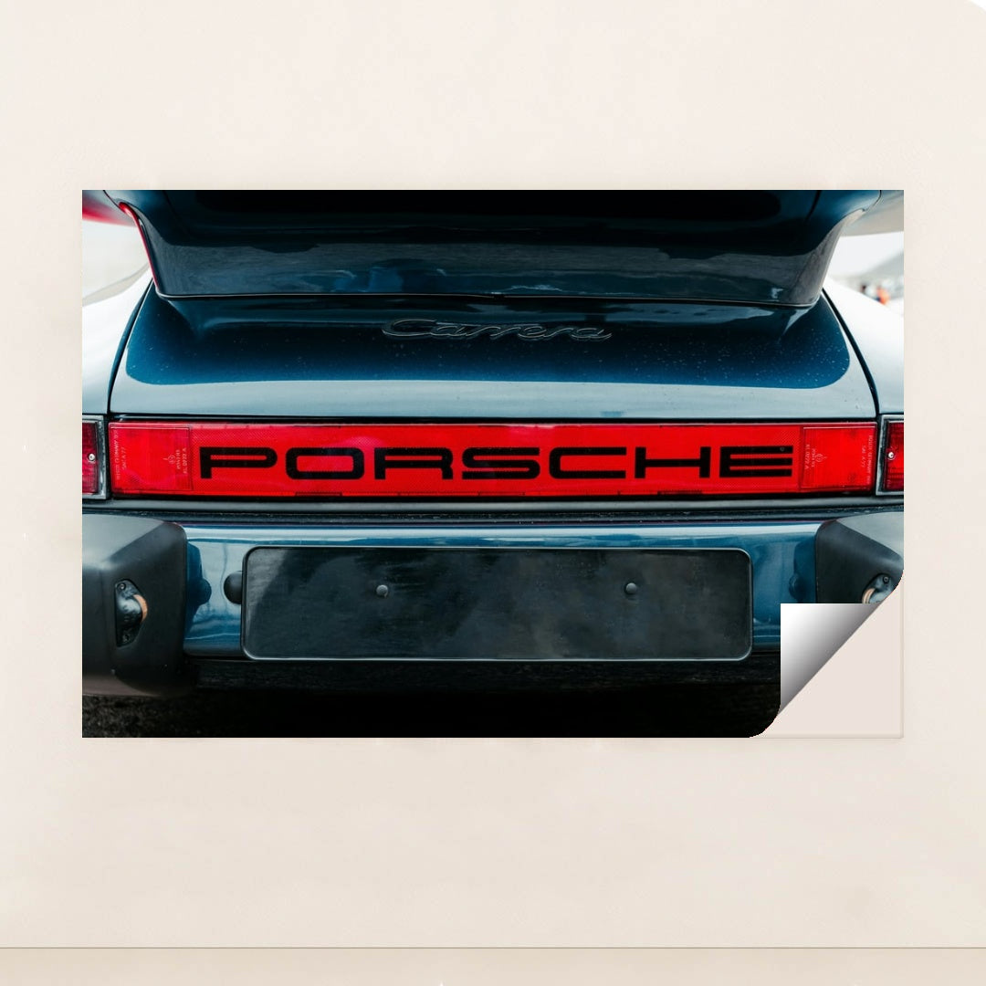 This photo shows the rear of a classic Porsche Carrera with a bold red Porsche logo and open trunk, unframed.