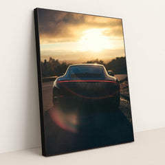 This photo shows the rear view of a Porsche sports car parked on a scenic hill at sunset with lens flare, in a black frame.