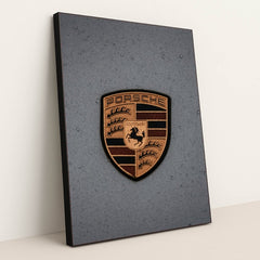 This photo features a gold Porsche emblem with raindrops on a gray car hood, in a black frame.