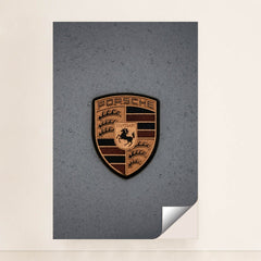 This photo features a gold Porsche emblem with raindrops on a gray car hood, unframed.