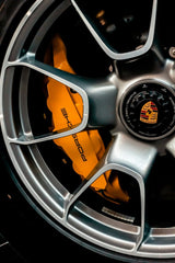 Close-up of a Porsche Precision Wheel showcasing satin silver alloy with bold yellow brake calipers for car wall art.