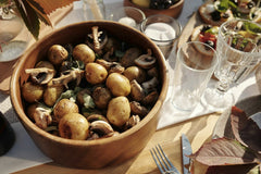 Askar Abayev - A rustic bowl of baby potatoes and mushrooms on a sunny dining table setting.