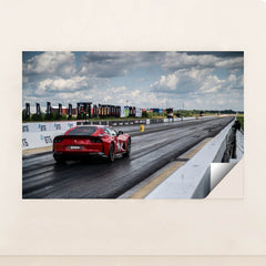 This photo shows a red Ferrari sports car on a dragstrip under a cloudy sky, ready to accelerate, minimalist unframed style.