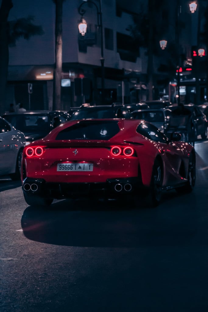 Ferrari 812 Superfast in the City, a striking red car moving through illuminated city streets at night.