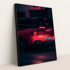 This photo shows a red Ferrari sports car driving at night, illuminated by neon lights, with a black Audi in the background, in a black frame.