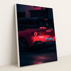 This photo shows a red Ferrari sports car driving at night, illuminated by neon lights, with a black Audi in the background, in a white frame.