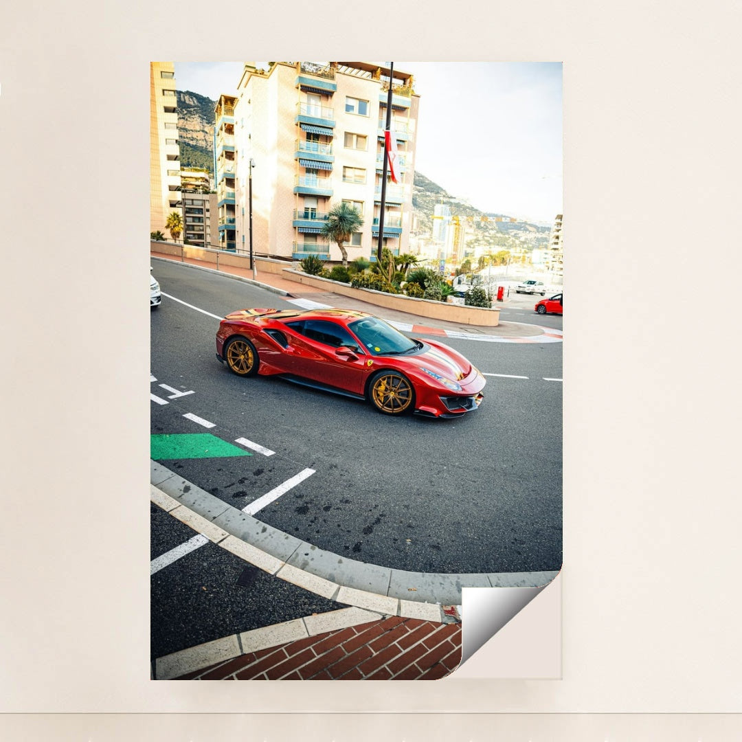 This photo shows a red Ferrari 488 Pista with gold wheels driving through a city street with Mediterranean buildings, unframed style.