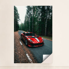 This photo shows a red Ferrari 812 Competizione with a white racing stripe parked on a winding forest road, unframed style.
