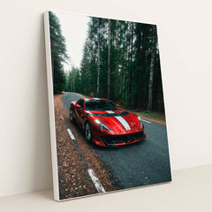 This photo shows a red Ferrari 812 Competizione with a white racing stripe parked on a winding forest road, in a white frame.