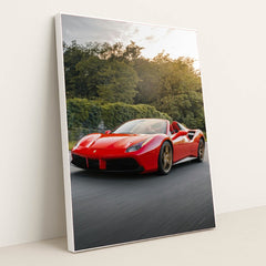 This photo shows a red Ferrari 488 Spider driving on a road with trees in the background, in a white frame.
